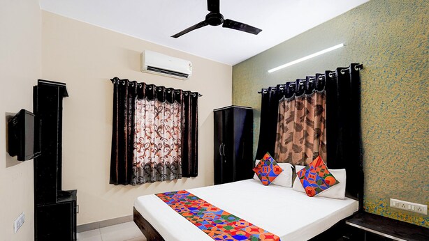 A bedroom with a bed, curtains, a ceiling fan, an air conditioner, and a wardrobe. - Via Seven Hills Inn (Mawal)