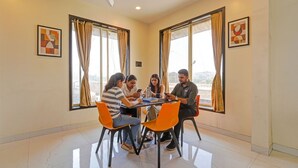 A group of people seated around a table in a room with large windows, a ceiling fan, and artwork on the walls. - Fabhotel Kv (Pen)
