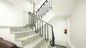 Un escalier au design moderne, doté d’une rampe en métal noir et de marches en granit.