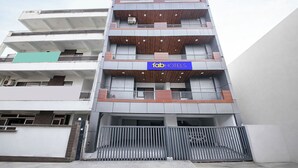 Un hôtel à plusieurs étages au design moderne, doté de balcons à chaque niveau et d’une enseigne distinctive.