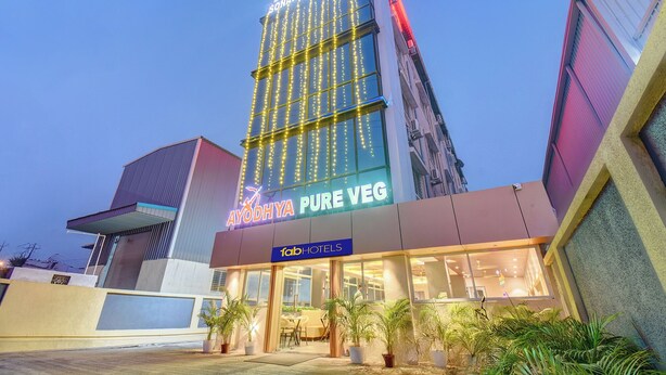 Een hotel met een moderne gevel, een bord met 'AYODHYA PURE VEG' en een bord met 'FOTOHOTELS'.