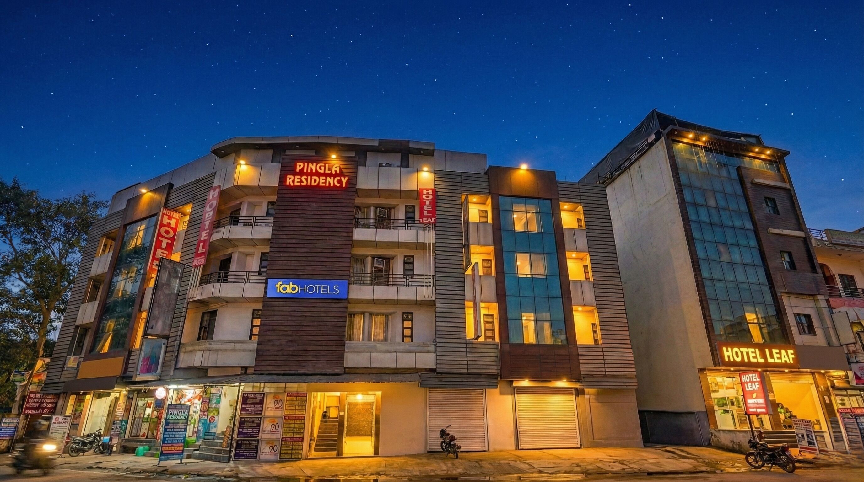 A multi-story building with signs for 'PINGLA RESIDENCY' and 'HOTEL LEAF'.