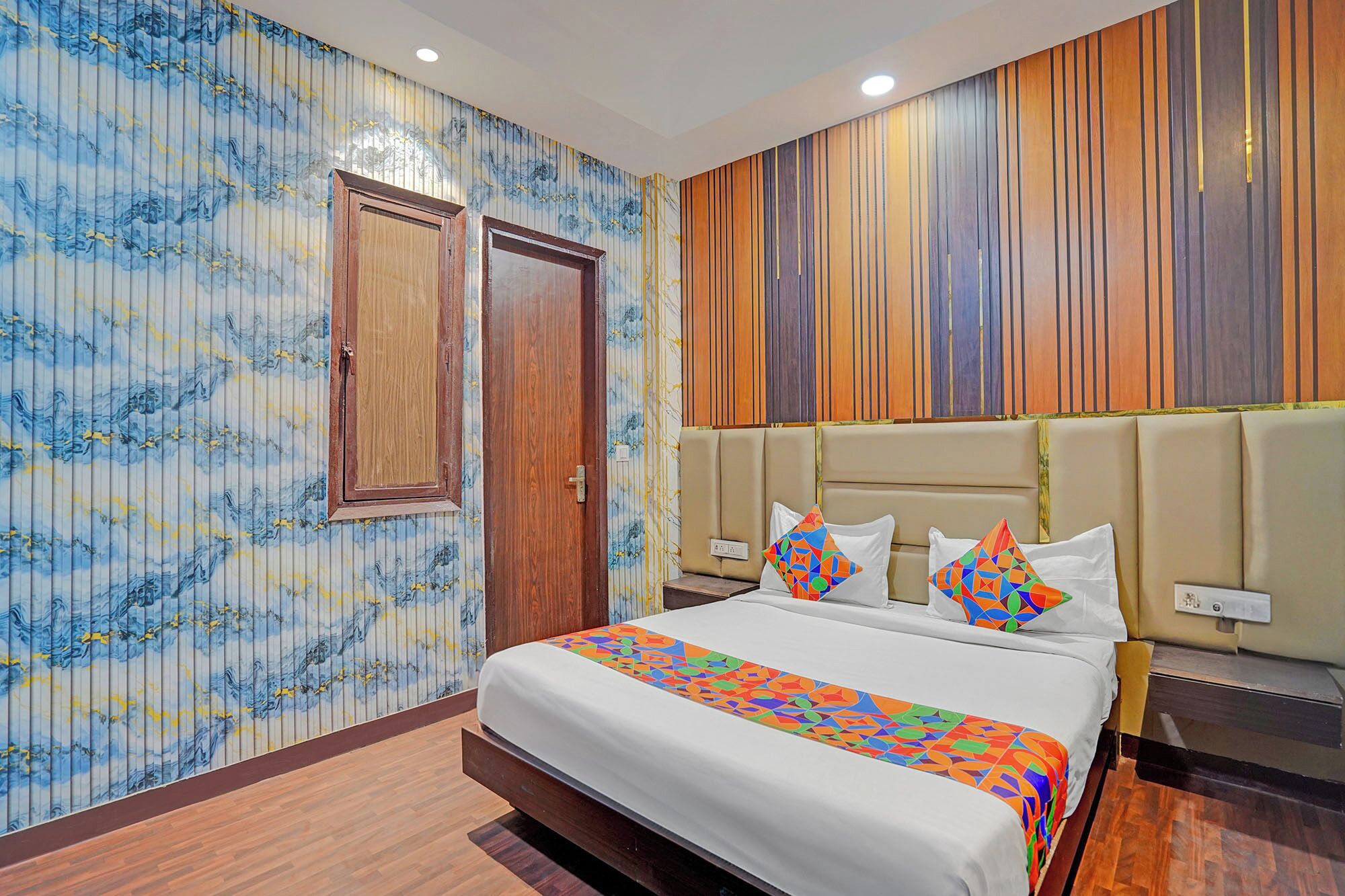 A hotel room with a large bed, a wooden door, and a wall with vertical wooden panels.