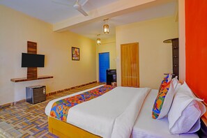 Habitación de hotel con una cama, televisor de pantalla plana montado en la pared, ventilador de techo y una puerta que da a otra habitación.