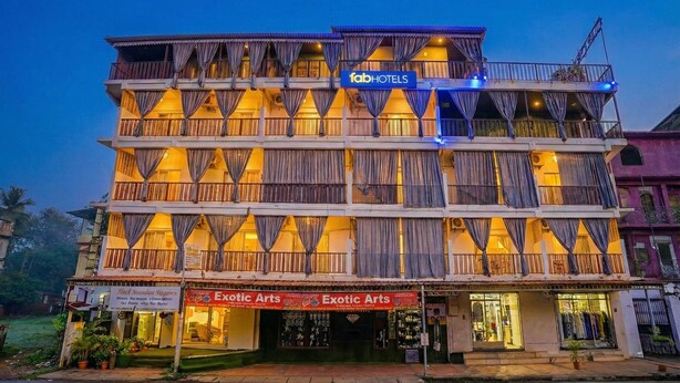 A multi-story building with balconies, a sign for 'fabHOTELS', and storefronts for 'Exotic Arts'. - Via Padma (Morjim)