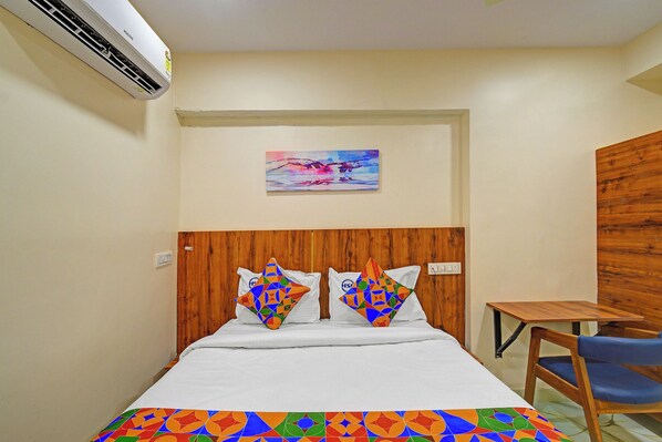 A hotel room with a bed, a painting on the wall, a wooden headboard, and a small table with a chair. - FabHotel S Continental - Kachiguda Railway Station, Kachiguda (Hyderabad)