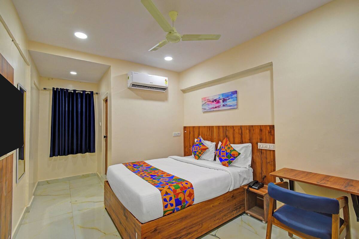 Une chambre d’hôtel équipée d’un lit, d’un bureau, d’une chaise, d’un ventilateur de plafond et d’un appareil de climatisation.