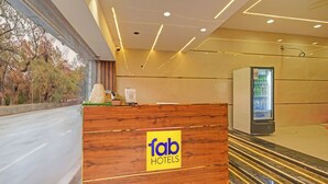 En receptionsdisk med träpanel och en gul skylt med texten ”fab hotels”.