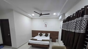 A hotel room with a bed, a ceiling fan, an air conditioning unit, and a window with curtains. - Fabhotel Nirmalvilla Corporate (Hyderabad)