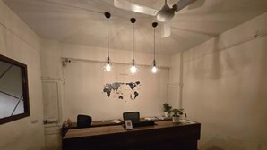 A reception desk with a world map, three pendant lights, and a ceiling fan. - Fabhotel Nirmalvilla Corporate (Hyderabad)