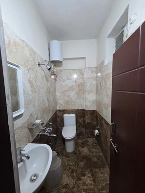 Un baño pequeño con lavamanos blanco, inodoro y zona de ducha.