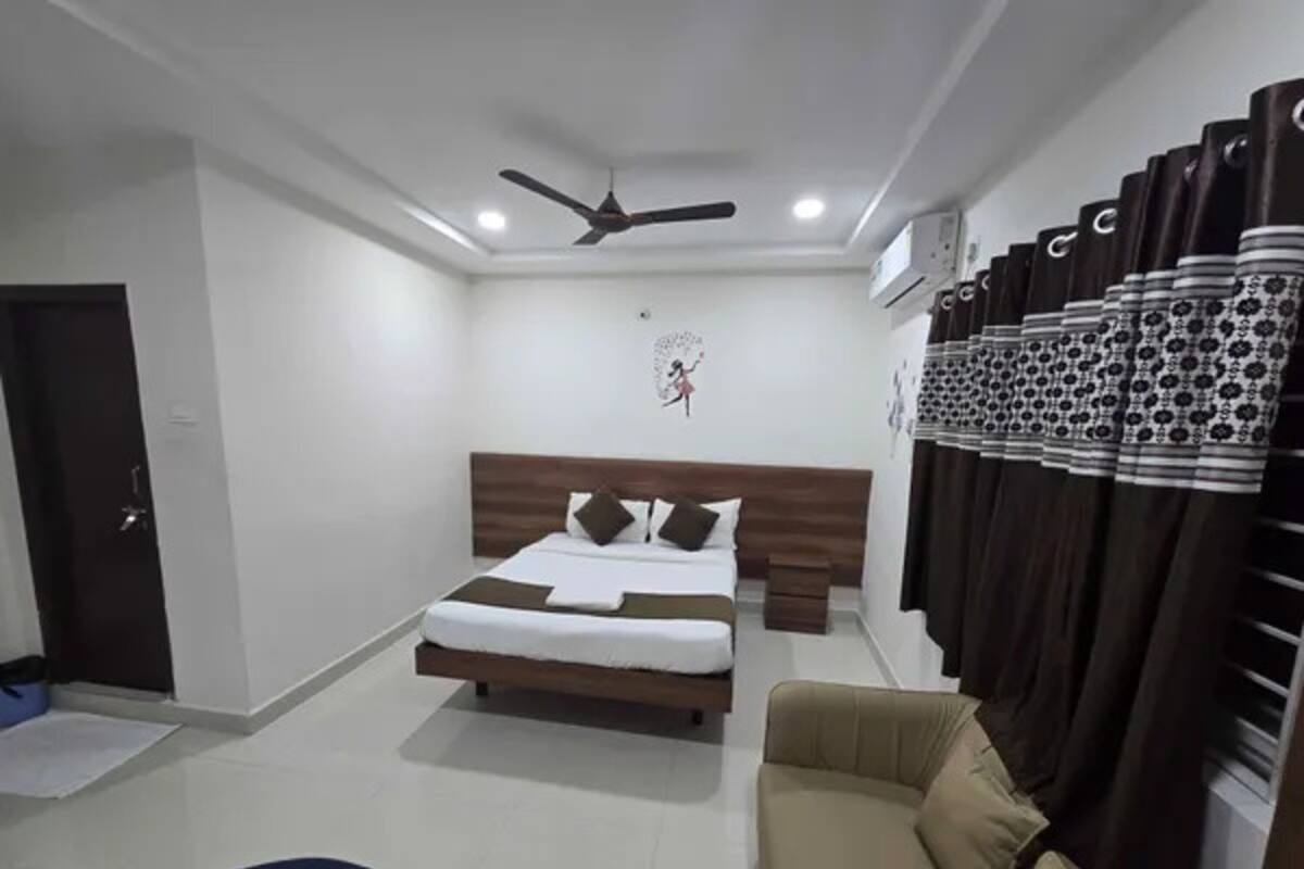 Un dormitorio moderno con cama, ventilador de techo, equipo de aire acondicionado y armario con cortinas estampadas.