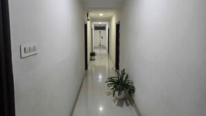 A clean, well-lit hallway with a potted plant and a security camera on the wall. - Fabhotel Nirmalvilla Corporate (Hyderabad)