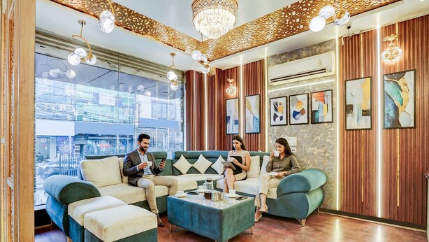 A modern lounge with a green sofa set, a coffee table, and a chandelier. - Fabhotel Raj Niwas (New Delhi)