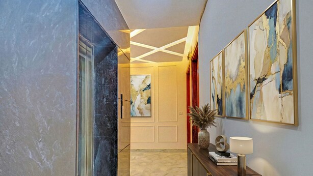A hallway with a marble floor, a wooden console table with a lamp, and abstract paintings on the wall. - FabHotel Premier Stays - 800m from Artemis Hospitals Gurgaon (Gurugram)