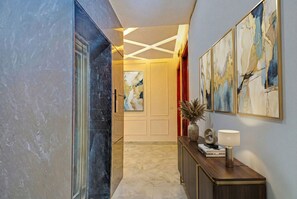 A hallway with a marble floor, a wooden console table with a lamp, and abstract paintings on the wall. - FabHotel Premier Stays - 800m from Artemis Hospitals Gurgaon (Gurugram)