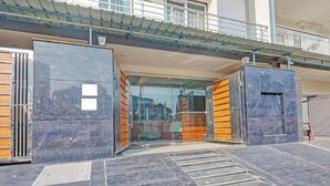 A building entrance with glass doors, a metal gate, and a ramp leading up to a balcony. - FabHotel Premier Stays - 800m from Artemis Hospitals Gurgaon (Gurugram)