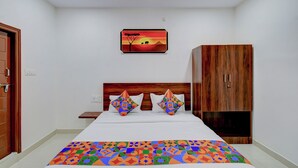 A bedroom with a bed, a wooden wardrobe, a nightstand, and a wall-mounted painting.