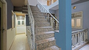 Ein mehrgeschossiges Interieur mit einer Treppe, einer Tür mit Fenster und einer Wand mit rundem Fenster.