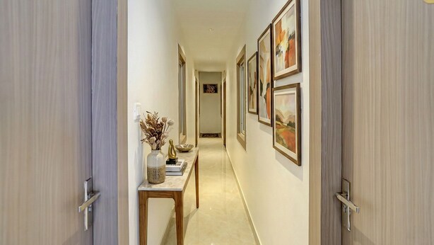 A hallway with a marble floor, framed artwork on the walls, and a small table with decorative items. - Fabhotel Swastik Villa (Varanasi)