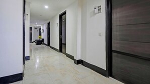 Un pasillo de hotel con suelo de baldosas, puertas cerradas y un ventilador de techo.