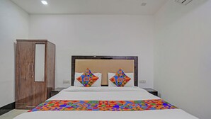Una habitación de hotel con una cama, un armario de madera y una pared blanca.