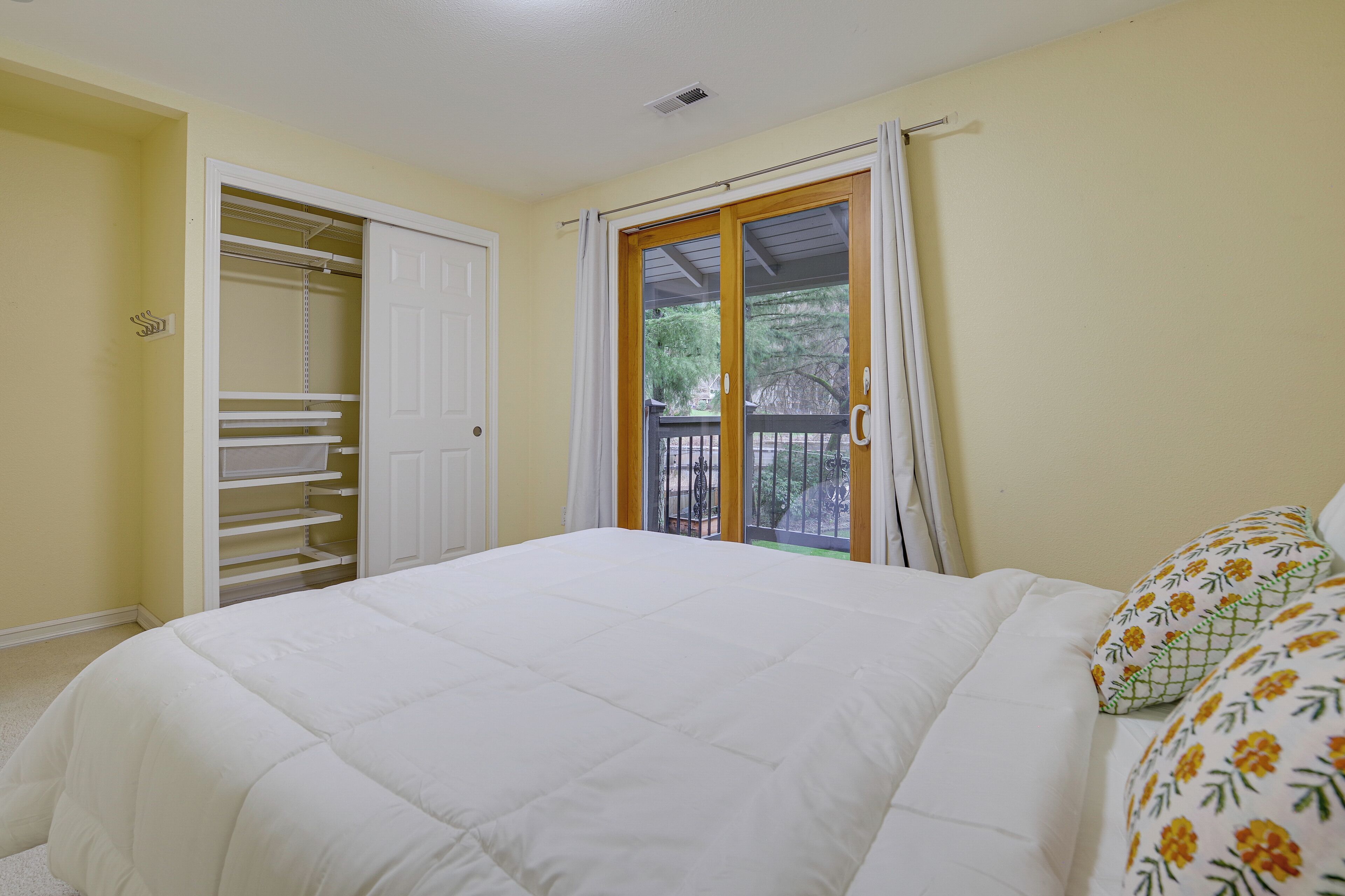 A bedroom with a bed, a wardrobe, and a sliding glass door to a balcony.