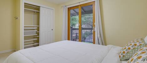 A bedroom with a bed, a wardrobe, and a sliding glass door to a balcony.