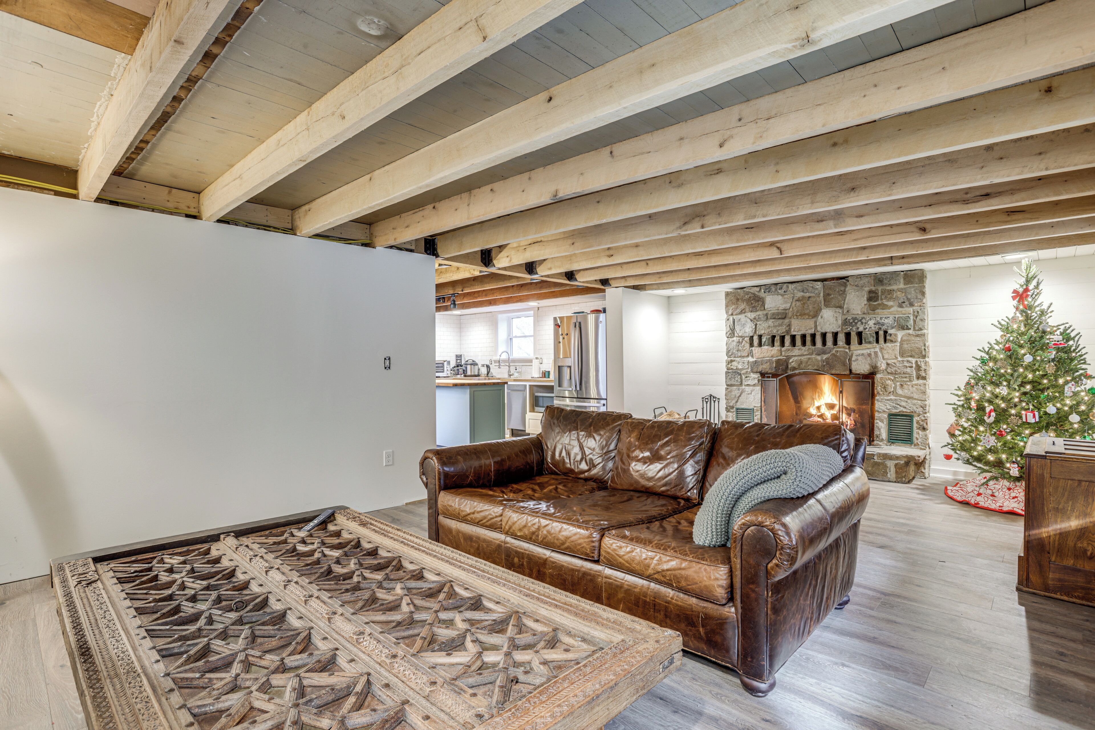 A spacious living room with a leather sofa, a wooden coffee table, and a stone fireplace.