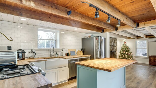 Una cucina moderna con travi in legno, un'isola grande, mobili bianchi e un albero di Natale.