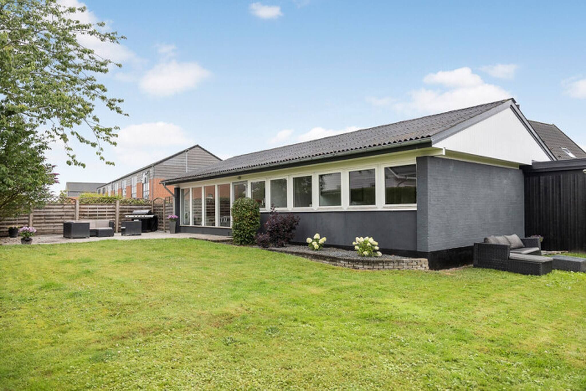 A modern house with a large attached garage, a covered patio, and a well-maintained lawn.