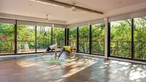 A spacious room with large windows, a ceiling fan, and a yoga mat on the floor. - Wonderful 1-bedroom apartment with AC in vibrant Tulum (Tulum)