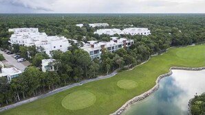 A modern residential area with white buildings, green lawns, and a body of water. - Wonderful 1-bedroom apartment with AC in vibrant Tulum (Tulum)