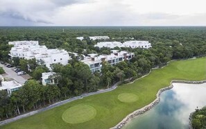 A modern residential area with white buildings, green lawns, and a body of water. - Wonderful 1-bedroom apartment with AC in vibrant Tulum (Tulum)