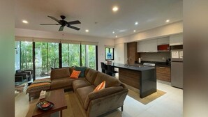 A modern living room with a sofa, coffee table, and a dining area. A kitchen with a central island and built-in appliances is visible. - Wonderful 1-bedroom apartment with AC in vibrant Tulum (Tulum)