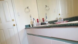 A kitchen with white cabinets, a pink and white rug, and a countertop with various items. - Warm place in beautiful Richmond (Richmond)