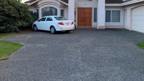 A two-story house with a driveway, a white car parked in front, and a garage. - Warm place in beautiful Richmond (Richmond)