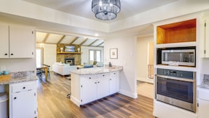 A modern kitchen with white cabinetry, a built-in microwave, and a large island with a granite countertop. - Waterfront Home on Greers Ferry Lake w/ Game Room (Edgemont)