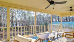 A covered outdoor deck with wooden furniture and a view of a forested area. - Waterfront Home on Greers Ferry Lake w/ Game Room (Edgemont)