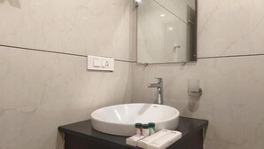Un baño con un lavabo redondo, un espejo y una encimera oscura.