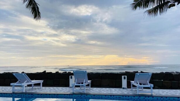 Una piscina con sillones de descanso y vista al océano.