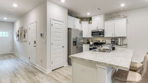 A modern kitchen with white cabinetry, a stainless steel refrigerator, a microwave, and a granite countertop. - 8 Mi to Dtwn Pensacola: Modern Escape w/ Patio! (Pensacola)