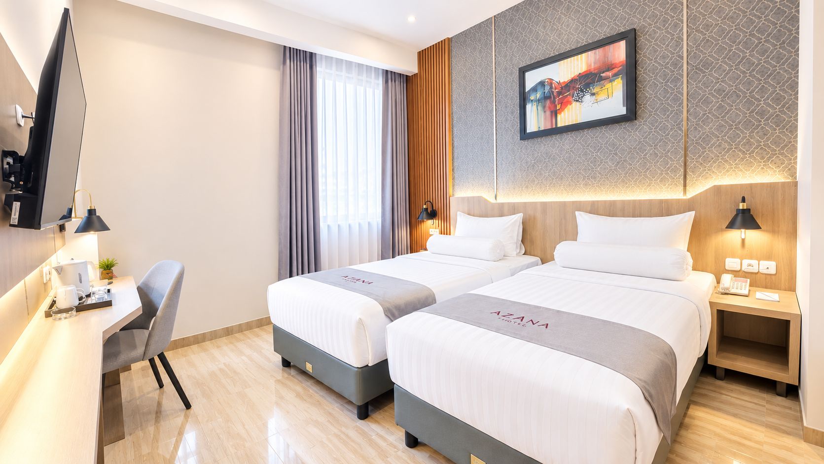 Habitación de hotel con dos camas, un escritorio, una silla, un televisor y un cuadro en la pared.