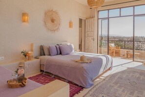 A bedroom with a large bed, a balcony with a view, and a rustic decor style. - Lalla Essaouira - Villa Koulchi, 10 bedroom, until 28 peop with staff (Essaouira)