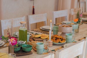 A dining table set with various dishes, including bread and pastries, and a candle. - Lalla Essaouira - Villa Koulchi, 10 bedroom, until 28 peop with staff (Essaouira)
