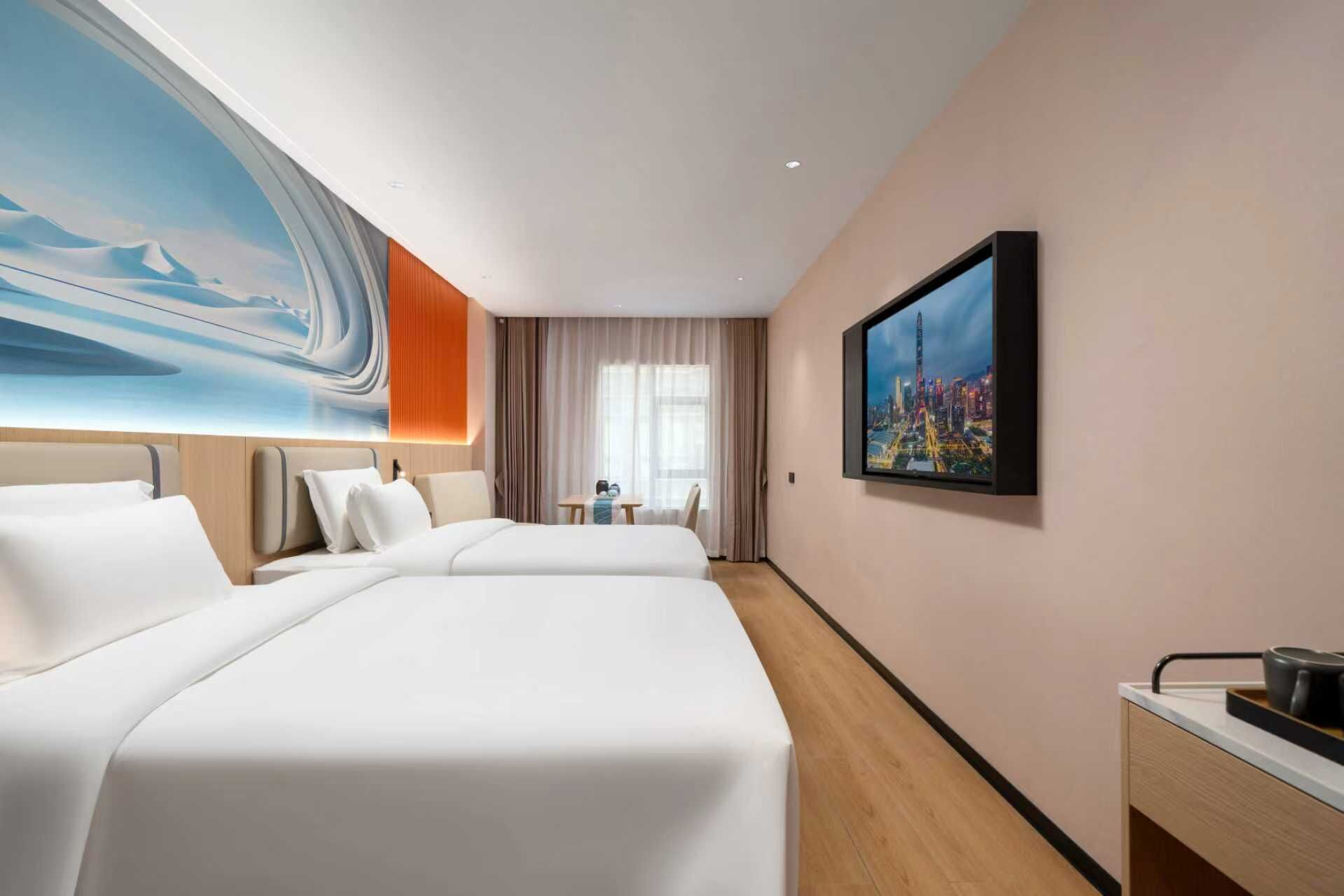 Une chambre d’hôtel avec deux lits, une grande fenêtre, un tableau représentant un paysage urbain et une petite table avec une tasse.