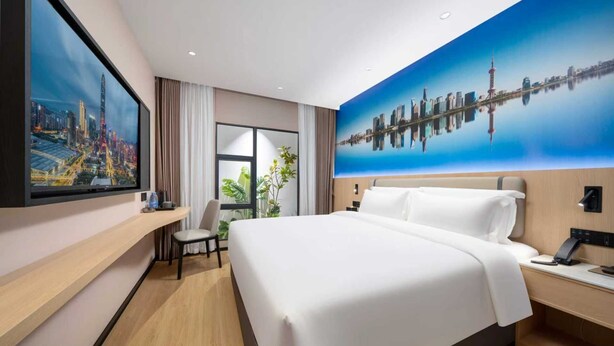 A hotel room with a large bed, a desk, a chair, a TV, and a cityscape mural on the wall. - Pengcheng Lijing Hotel  (Shenzhen)