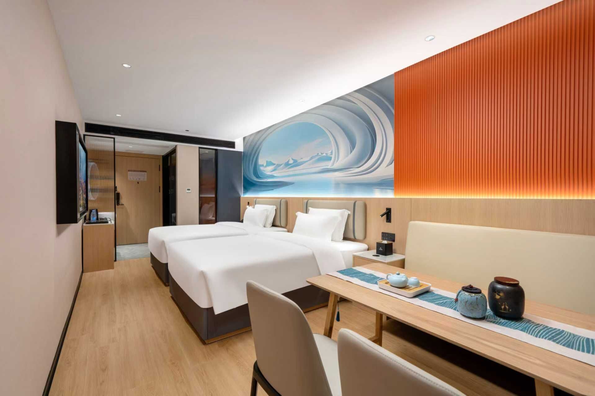 A hotel room with two beds, a desk, and a large wall mural.