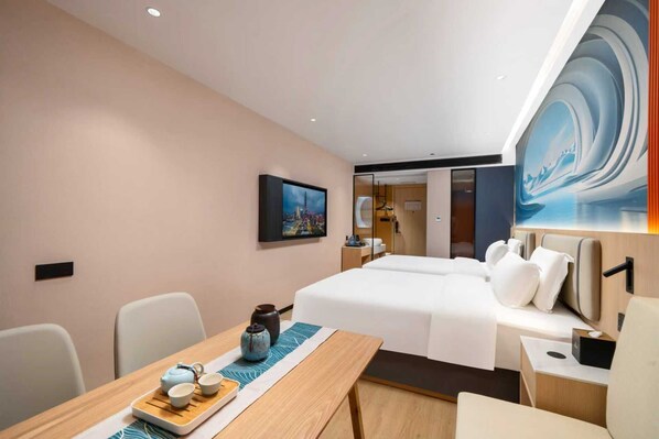 A hotel room with a bed, bedside tables, a desk with a teapot and cups, and a painting on the wall. - Pengcheng Lijing Hotel (Shenzhen)