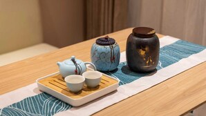A wooden table with a tray holding a teapot, two cups, and a ceramic vase. - Pengcheng Lijing Hotel  (Shenzhen)